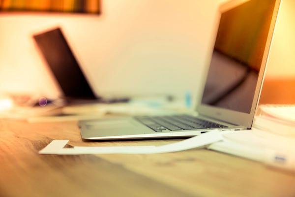 Two laptops with a notepad for essay writing - Scribbr