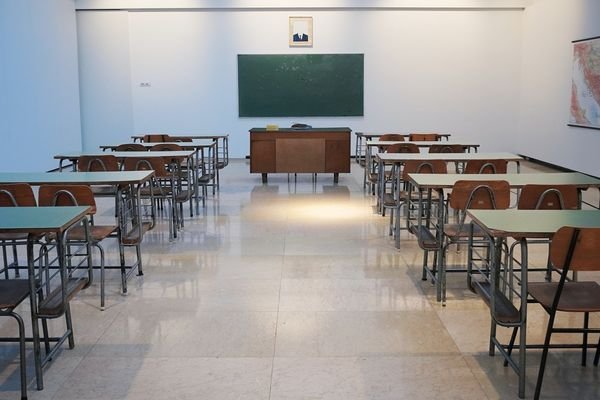 School Classroom with Multiple Two-Seater Desks With Teachers Desk in Center of Frame Preparing for AI Checker Essay Lecture