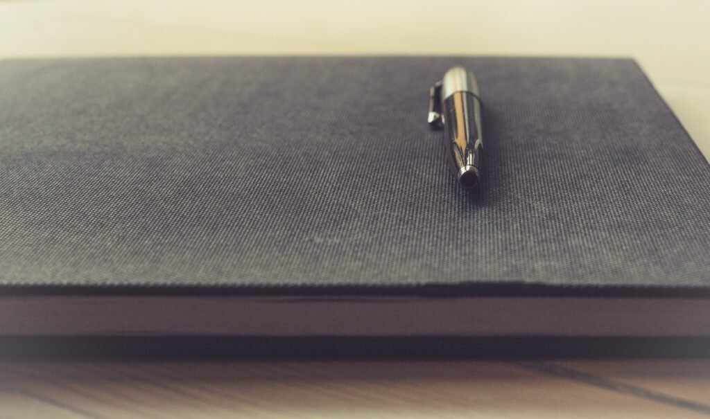 pen on a black notebook - how to write a persuasive essay