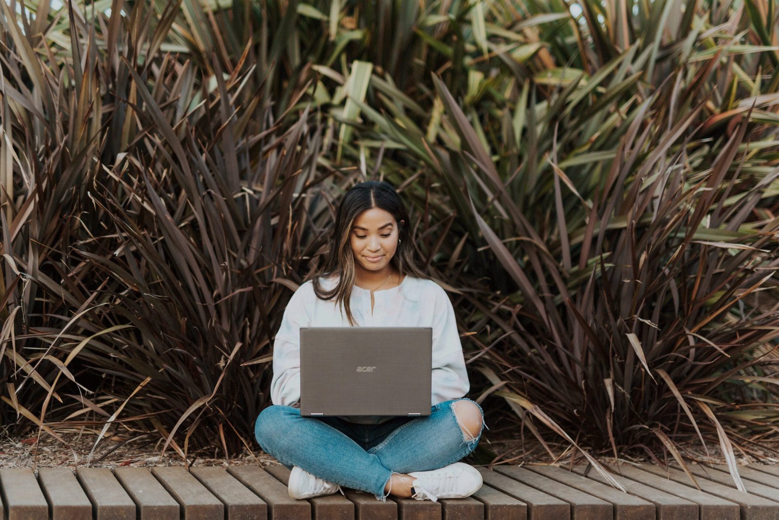 woman happily sitting outdoor and working with laptop - what is the best citation generator