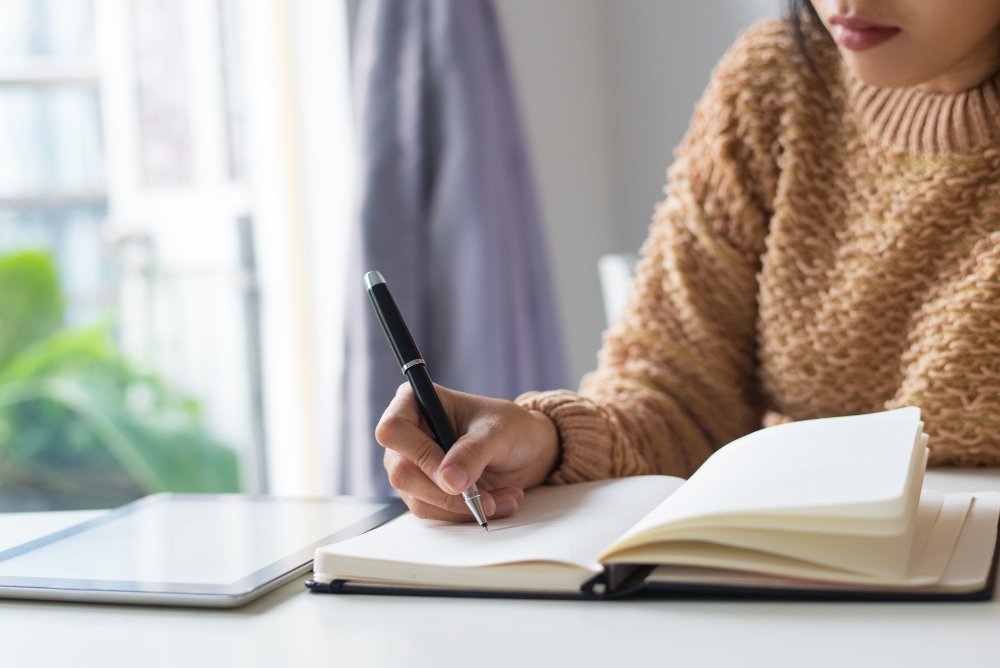 woman writing on a book - Essay About Death