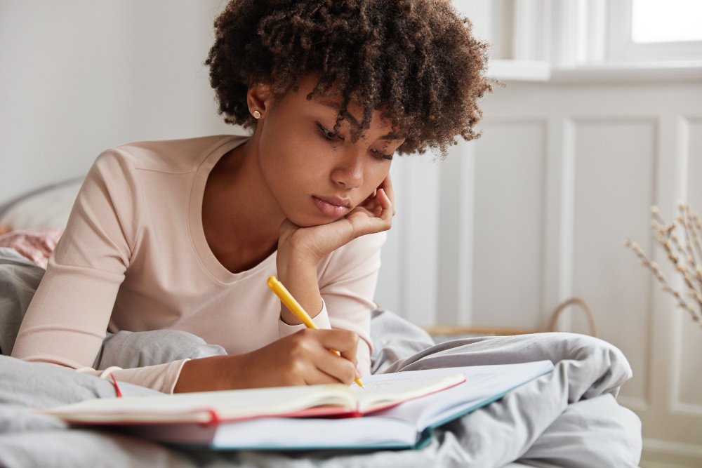 woman lying on bed and writing - National Honor Society Essay Examples		
