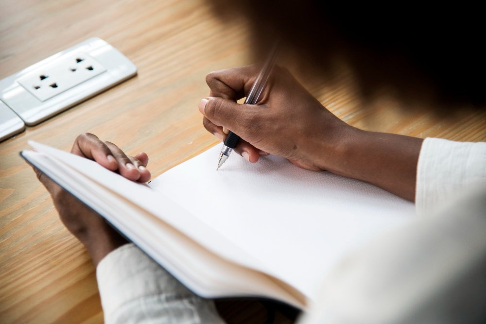 woman writing on a book - Proposal Essay Examples